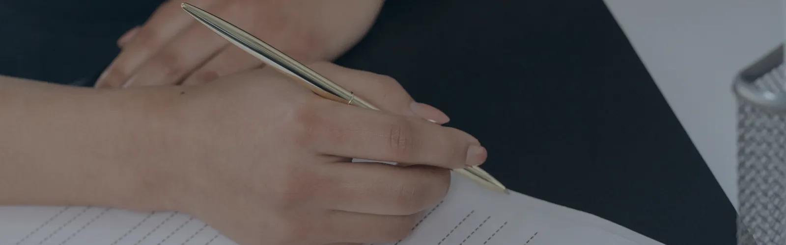Hands holding a gold pen over a blank form on a clipboard